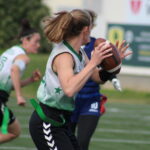 QB Stefi Hirscher ist von hinten zu sehen wie sie bereit ist, den Ball zu einer Receiverin zu werfen