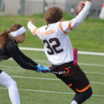 Defender pulling the flag of a receiver holding the ball mid run
